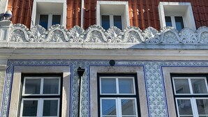 A building with ornate white railings, three windows with red-tiled roofs, and a blue and white patterned facade. - Apart 3Bdr with River view and private Patio - Center of Lisbon (Lisboa)