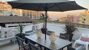 Un espace extérieur aménagé avec une table, des chaises et un grand parasol.