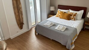A bedroom with a bed, a wooden headboard, a nightstand with a lamp, a large window, and a view of the outside. - Apart 3Bdr with River view and private Patio - Center of Lisbon (Lisboa)