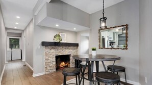 A dining area with a round table and four stools, a fireplace, and a mirror with an ornate frame. - Spacious 5 Bedroom Duplex In Kansas City! 65/66 (Kansas City)