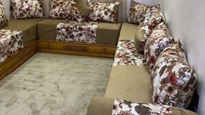 A cozy living room with a sofa set, floral cushions, and a large window with curtains. - Casa. Aziz (Chefchaouen)