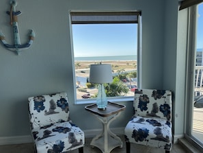 Enjoy a serene coastal view from the comfort of this room, featuring a window with a view of the ocean and a nearby building.