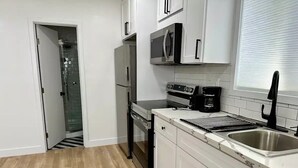 A modern kitchen with white cabinets, stainless steel appliances, and a wooden floor. - Airy Arty Studio with Amenities (Gardena)