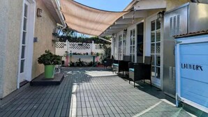 A covered patio area with a tiled floor, outdoor seating, and a laundry room.