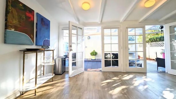 A spacious room with wooden flooring, a coffee table, and a painting on the wall.