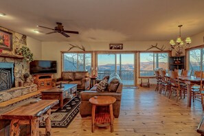 Amplia sala de estar con chimenea, un televisor grande y un comedor con muebles de madera.