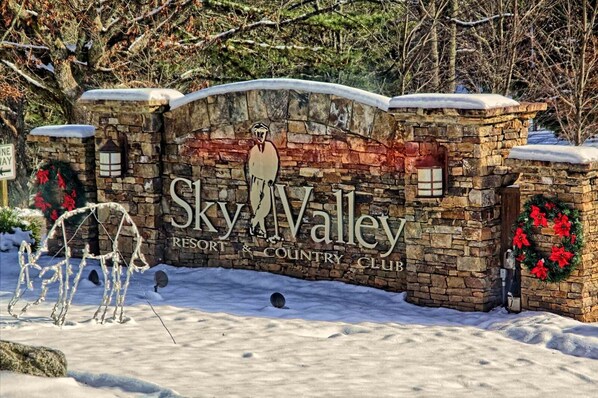 Puerta de piedra con el texto "Sky Valley Resort & Country Club" y adornos de coronas decorativas.
