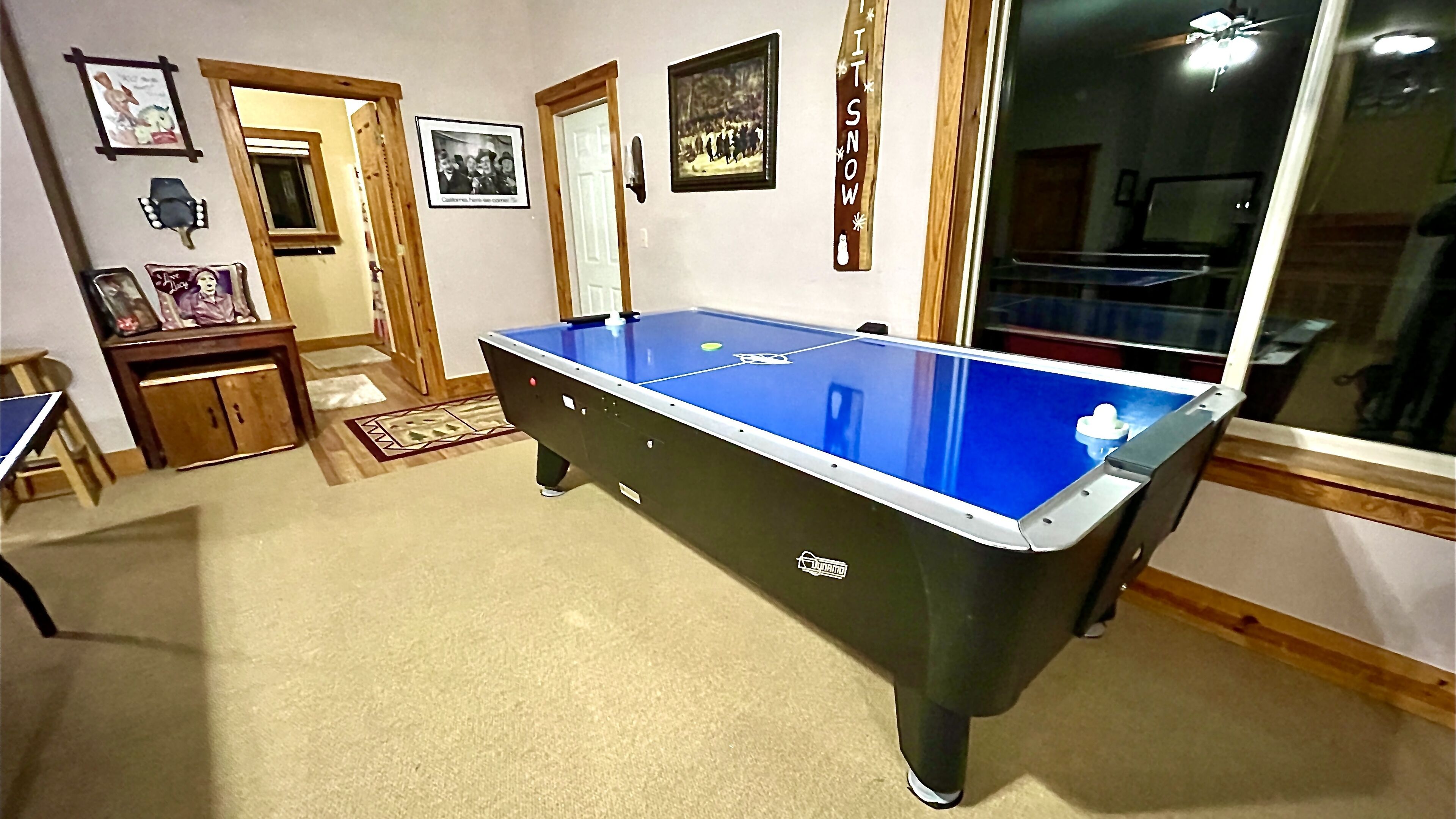 A pool table in a room with wooden flooring, a door, and a window.