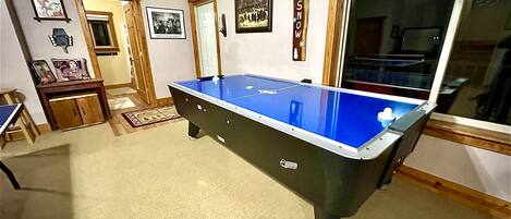 A pool table in a room with wooden flooring, a door, and a window.