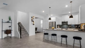 Une cuisine moderne dotée d’un îlot central, de tabourets de bar et d’appareils électroménagers en acier inoxydable.
