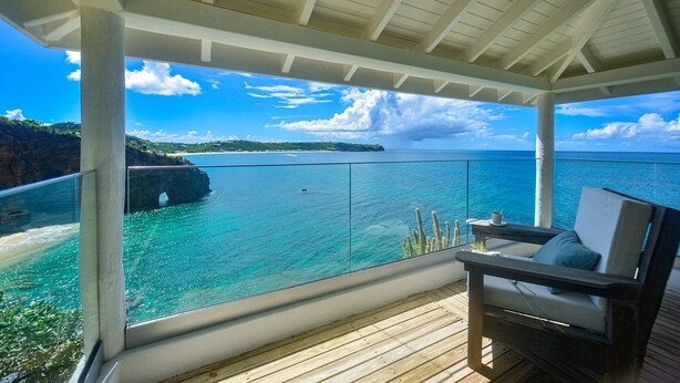 En balkon med udsigt over havet og en klippefyldt kystlinje.