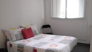 Une chambre à coucher avec un lit, des oreillers, une chaise et une fenêtre.