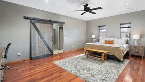 A bedroom with a bed, bedside tables, a ceiling fan, a sliding door, and a wooden bench. - Western desert escape, pool, backyard oasis (Phoenix)