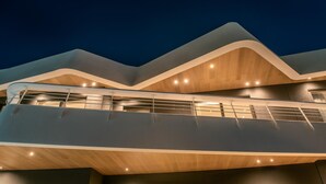 A modern building with a unique wavy roof design and a glass balcony. - Made By The Sea Villas 8 Bdrm (Malevizi)