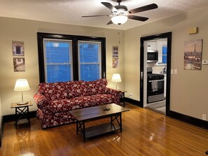 A living room with a sofa, two lamps, a coffee table, and a ceiling fan.