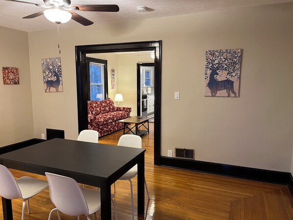 A dining area with a table and chairs, a ceiling fan, and artwork on the walls.