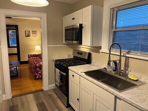 A compact kitchen with white cabinets, a stainless steel stove, and a built-in microwave.