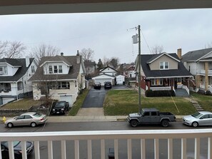 A residential street with houses, a driveway, and parked cars.
