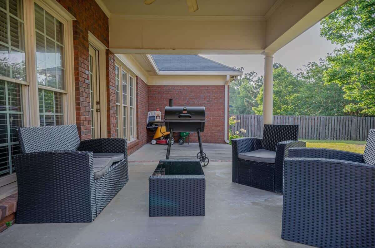 An outdoor patio with wicker furniture and a barbecue grill.