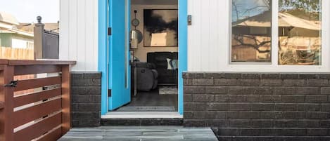 A modern house with a blue door, a stone pathway leading to the entrance, and a brick wall.