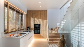Een moderne keuken met houten kastjes, een ingebouwde oven en een koffiezetapparaat.