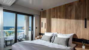 Een moderne hotelkamer met een groot bed, een wand van houten panelen en een balkon met uitzicht op zee.