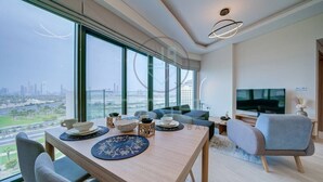 Un salon moderne comprenant un coin repas, de grandes fenêtres, un téléviseur à écran plat et une vue sur la ville.