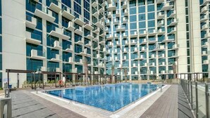 Un hôtel moderne doté d’une piscine sur le toit, entouré d’un immeuble de grande hauteur avec des balcons.