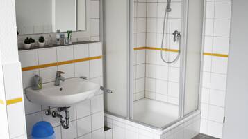Ein Badezimmer mit Waschbecken, Spiegel und Duschkabine.