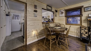 A wooden interior with a dining table, chairs, a window with blinds, and a fireplace with wood logs. - Rustic Cozy Cabin at the base of Greenhorn Mountain. (Rye)