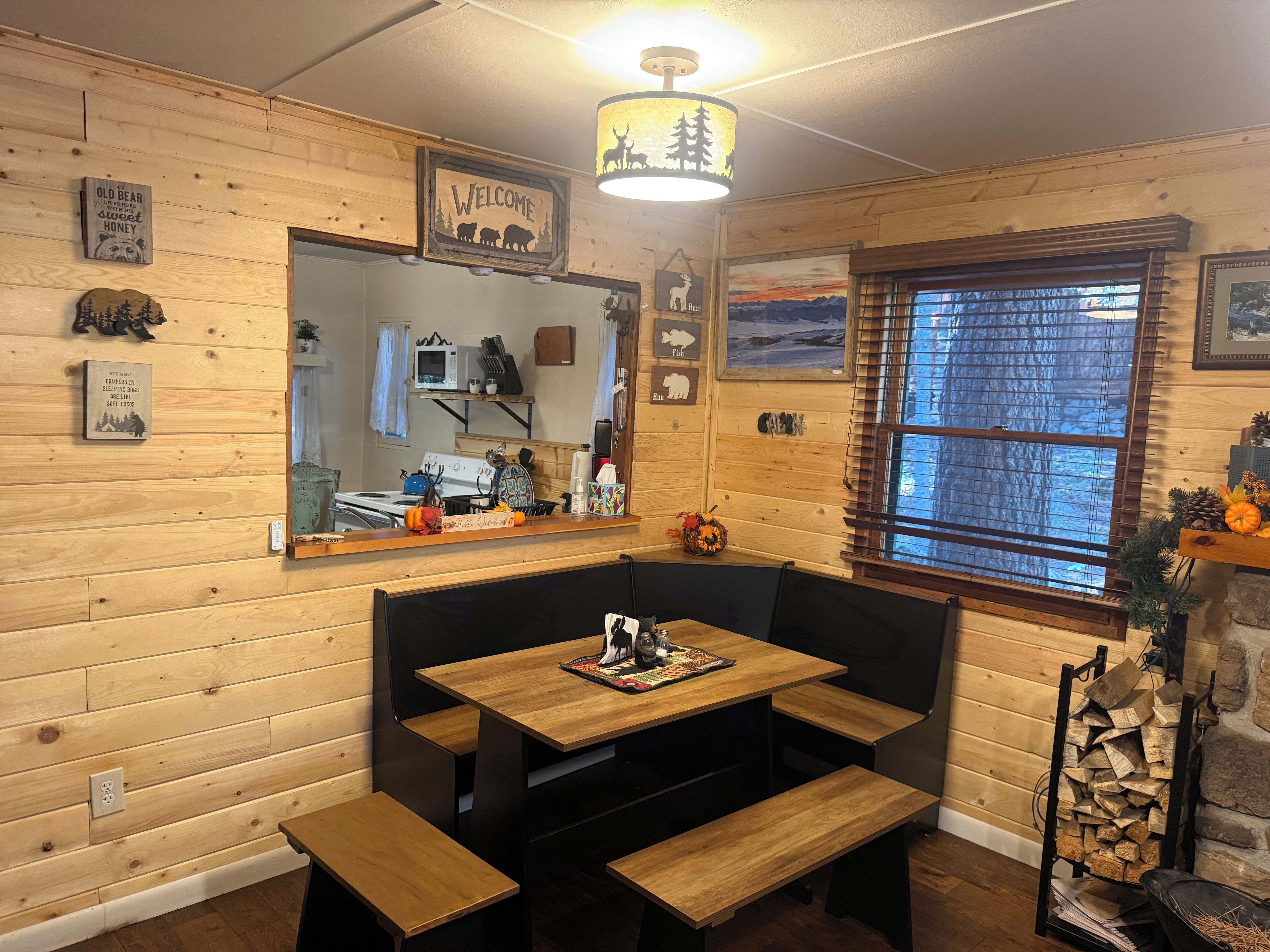 A cozy cabin interior with wooden walls, a wooden bench, a table, and a window with blinds.