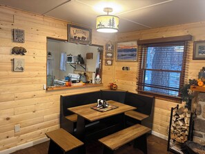A cozy cabin interior with wooden walls, a wooden bench, a table, and a window with blinds. - Rustic Cozy Cabin at the base of Greenhorn Mountain. (Rye)