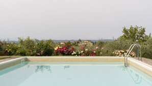 Una piscina amb vora de rajola, envoltada de flors i vegetació de colors.