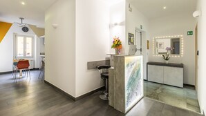 Un espace d’accueil comprenant un comptoir, des chaises, un vase de fleurs et un miroir avec éclairage.