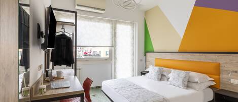 Una habitación de hotel con cama, escritorio, silla y ventana con cortinas.