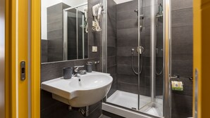 Une salle de bain moderne avec une douche à parois de verre, un lavabo blanc et un miroir au-dessus du lavabo.
