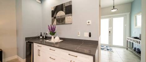 A kitchen with a marble countertop, white cabinets, and a decorative wall piece.