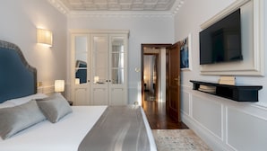 Een slaapkamer met een groot bed, een aan de muur bevestigde televisie en een kledingkast met spiegel.