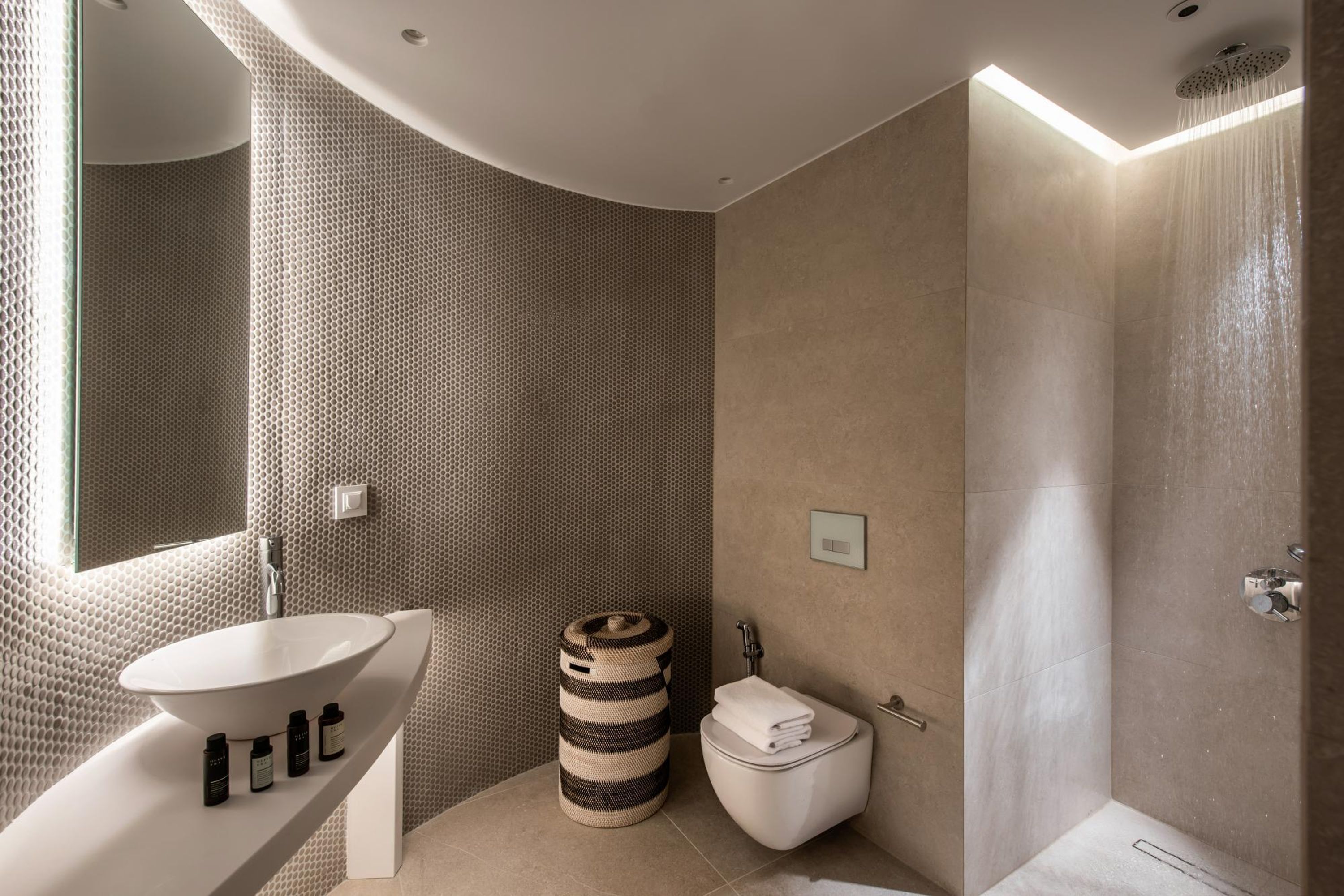 Ein modernes Badezimmer mit einem runden Waschbecken, einer Toilette und einer Dusche.