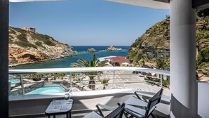 A balcony with a pool, chairs, and a clear view of the coastline and ocean.