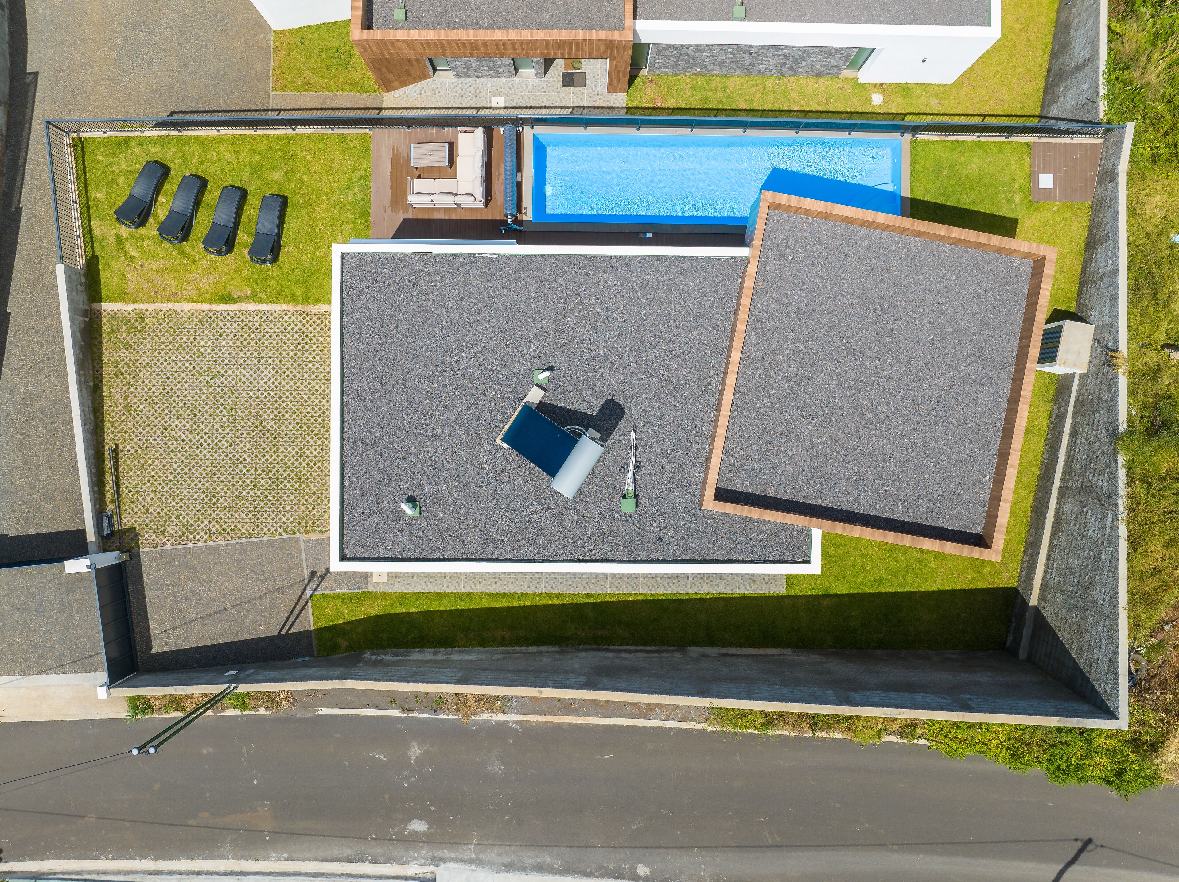 Vue aérienne d’un toit-terrasse aménagé avec une piscine, des chaises longues et un petit espace de détente.