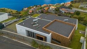 Un edificio moderno con tetto piatto, un'ampia vetrata e vista sull'oceano.