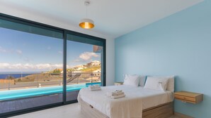 Camera da letto moderna con un'ampia finestra, un letto con lenzuola bianche e un comodino in legno.