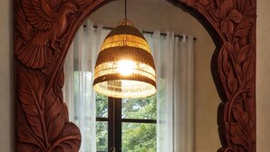 Ein Zimmer mit Bett, einem Fenster mit Vorhängen und einer Pendelleuchte.