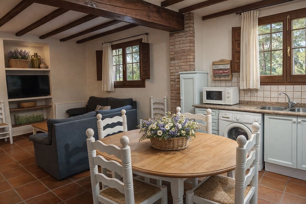 Una sala de estar acogedora con un sofá azul, una mesa de comedor de madera con sillas, un televisor y una zona de cocina con lavadora.