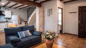 Ein Wohnzimmer mit einer Couch, einem Couchtisch und einem Blumenstrauß. Eine Treppe führt in einen anderen Raum.