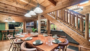 A wooden interior with a dining area featuring a long table, chairs, and a staircase. - Family friendly! 3King+Bunk|PingPong|PoolTbl|Private (Pigeon Forge)