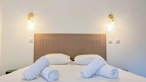 Habitación de hotel con una cama bien hecha, dos lámparas de pared y un cabecero con diseño geométrico.