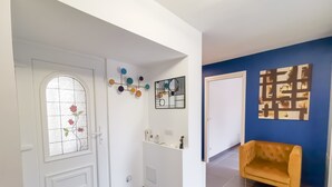 Un interior moderno con una puerta blanca, una pared azul como acento y un sillón amarillo.
