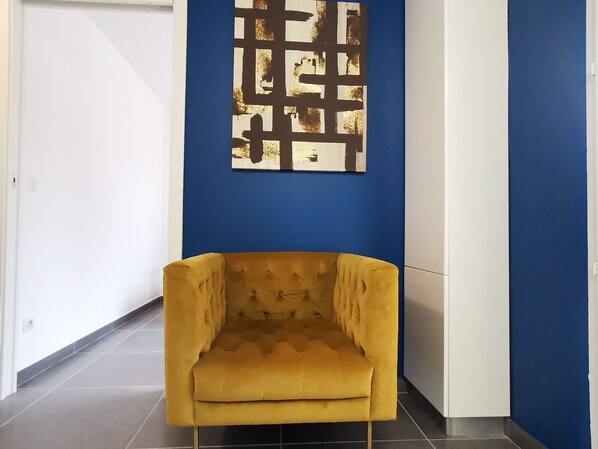 A room with a yellow armchair, a blue accent wall, and a white door.